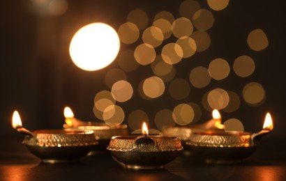 Lit diya lamps on dark table. Diwali celebration