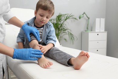 Doctor checking boy's leg with bruise at hospital