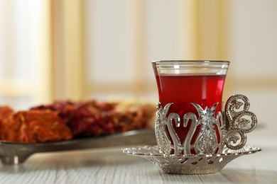 Photo of Glass of traditional Turkish tea in vintage holder on white wooden table. Space for text