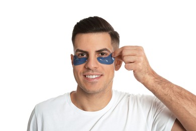 Man applying blue under eye patch on white background