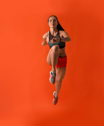 Athletic young woman running on red background