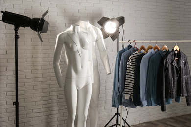 Ghost mannequins, clothes and professional lighting equipment in modern studio. Fashion photography