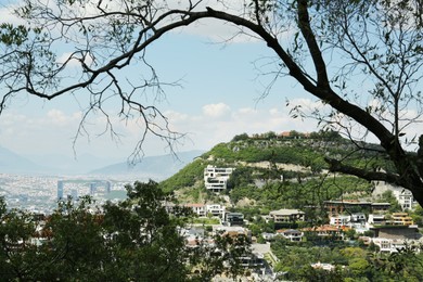 Photo of Picturesque view of trees, buildings and mountains in city