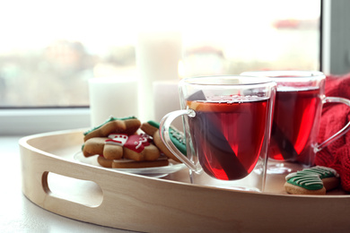 Cups of delicious mulled wine and cookies on window sill indoors, closeup. Winter drink