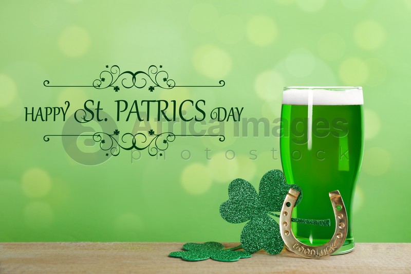 Green beer, horseshoe and clover leaves on wooden table. St. Patrick's Day celebration