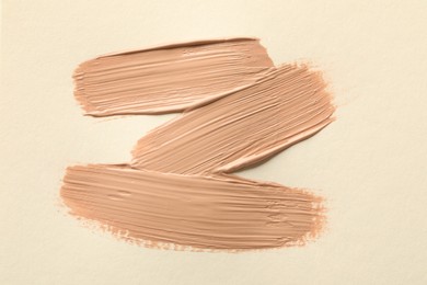 Sample of liquid skin foundation on beige background, top view