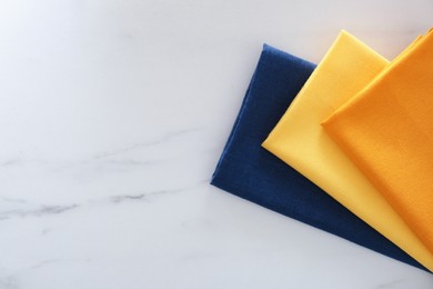 Colorful napkins on white marble table, top view. Space for text
