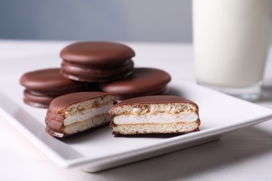 Tasty choco pies and milk on white wooden table, closeup view