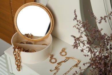 Jewelry box with mirror and stylish golden bijouterie on table
