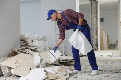 Construction worker with used building materials in room prepared for renovation