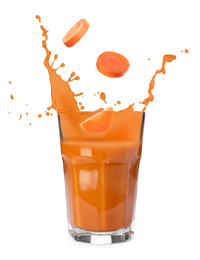 Carrot slices falling into glass of fresh juice with splashes on white background