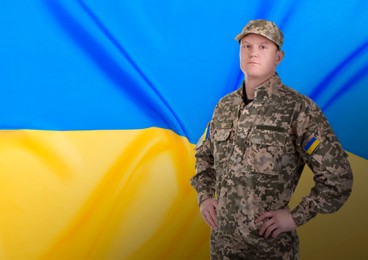 Soldier in military camouflage uniform and Ukrainian flag on background, space for text. Stop war