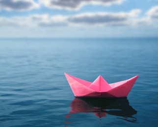 Pink paper boat floating on calm sea 