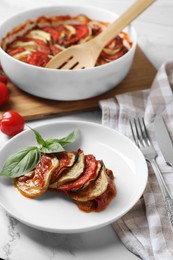 Photo of Delicious ratatouille served with basil on white marble table, closeup