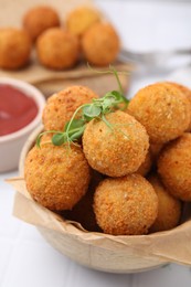 Photo of Bowl of delicious fried tofu balls with pea sprouts and ketchup on white tiled table, closeup