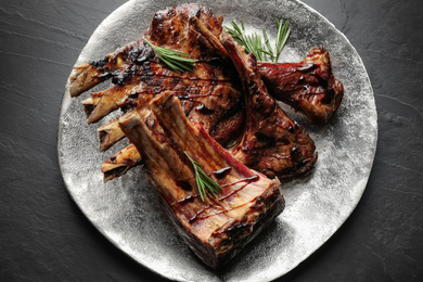 Delicious grilled ribs served on black table, top view