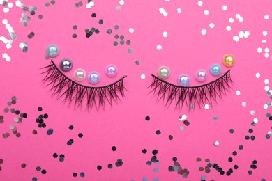 Photo of Flat lay composition with false eyelashes, beads and confetti on pink background