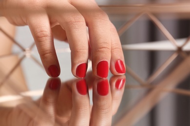 Woman with red manicure on mirror surface, closeup. Nail polish trends