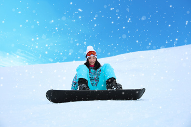 Young woman snowboarding on hill at mountain resort. Winter vacation