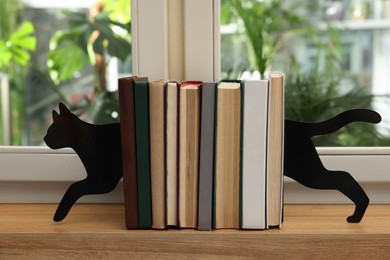 Photo of Minimalist cat bookends with books on window sill indoors