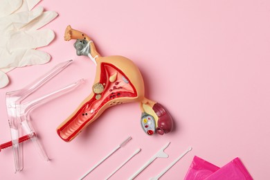 Gynecological examination kit and anatomical uterus model on pink background, flat lay. Space for text