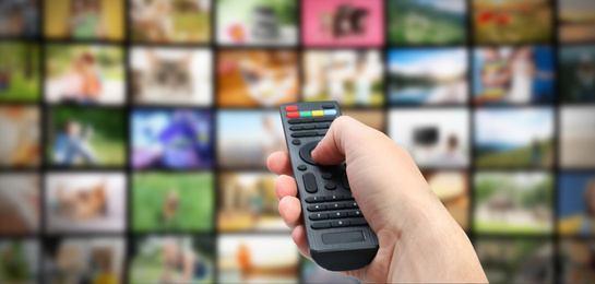 Streaming video services. Man using remote control to change channels on TV, closeup