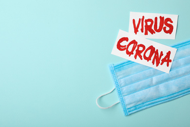 Phrase CORONA VIRUS and medical mask on light blue background, flat lay. Space for text
