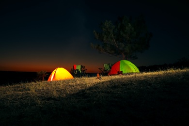 Camping tents and chairs in wilderness at night