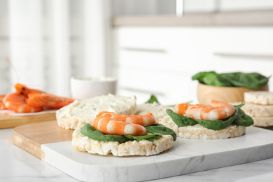 Puffed rice cakes with shrimps and basil on white marble table indoors