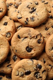 Photo of Many delicious chocolate chip cookies as background, top view