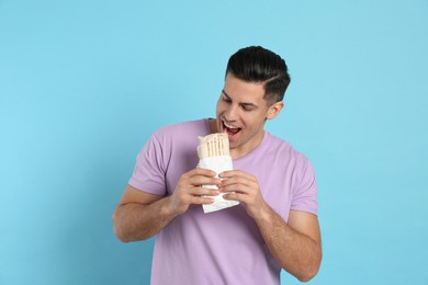 Photo of Man eating delicious shawarma on turquoise background