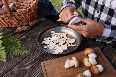 Man slicing mushrooms at wooden table outdoors, closeup