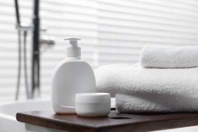 Photo of Stacked bath towels and personal care products on tub tray in bathroom, closeup