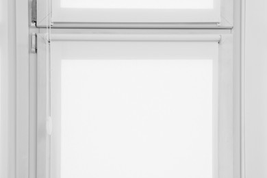 Window with closed white roller blinds indoors