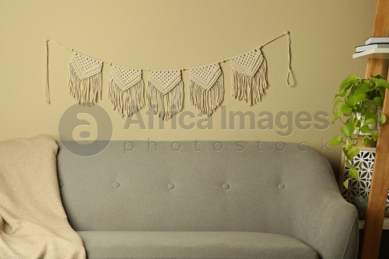 Beautiful large macrame hanging on beige wall in living room. Decorative element