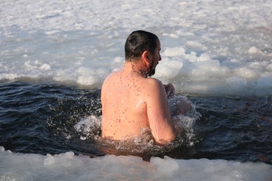 MYKOLAIV, UKRAINE - JANUARY 06, 2021: Man immersing in icy water on winter day, back view
