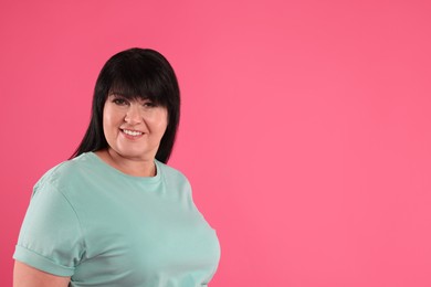 Beautiful overweight mature woman with charming smile on pink background. Space for text