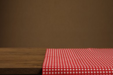 Red and white checkered tablecloth on wooden desk, space for design