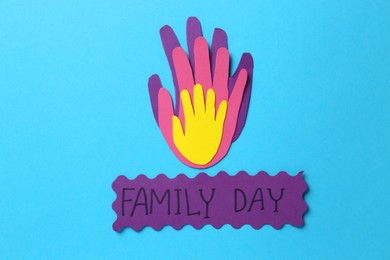 Card with text Family Day and paper palms on light blue background, flat lay