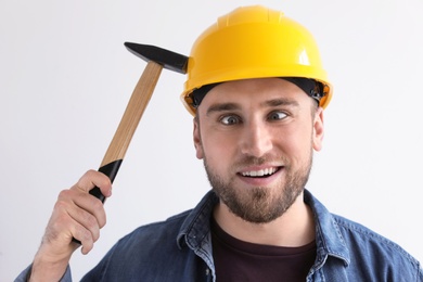 Funny young working man in hardhat with hammer on white background