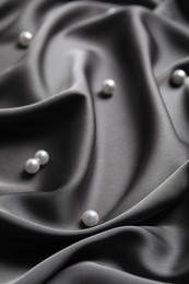 Many beautiful pearls on delicate black silk, closeup