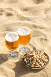 Photo of Glasses of cold beer and pistachios on sandy beach