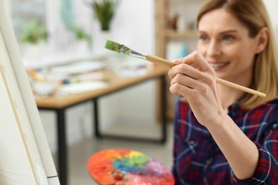 Photo of Woman painting on canvas in studio, selective focus. Creative hobby
