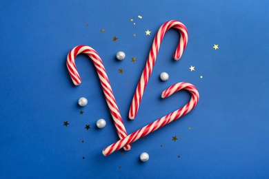 Candy canes on blue background, flat lay. Christmas treat