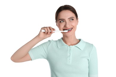 Young woman brushing teeth with charcoal toothpaste on white background