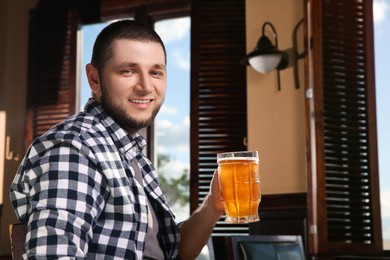 Man with glass of tasty beer in pub