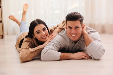 Happy couple lying on warm floor at home. Heating system