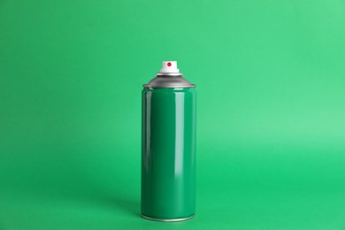 Colorful can of spray paint on green background