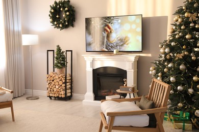 Modern TV set on light wall in room decorated for Christmas