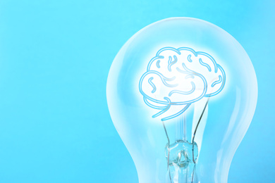 Lamp bulb with human brain inside on light blue background, space for text. Idea generation